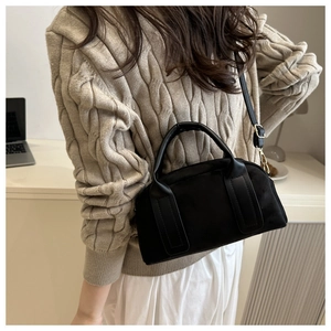 Detailansicht der schwarzen Wildledertasche kombiniert mit beigem Strickpullover