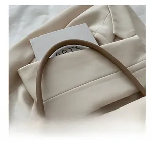 Gros plan du sac à main beige minimaliste avec détail de poignée marron foncé contrasté