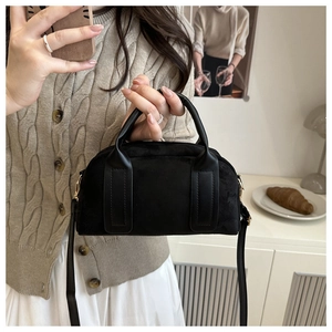 Detail der schwarzen Wildleder-Boston-Tasche mit glatten Ledergriffen und Schultergurt