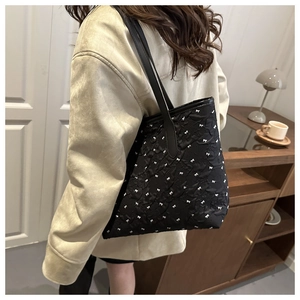 Détail d'un sac cabas noir à texture gaufrée et motifs de petits nœuds blancs élégants