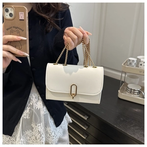 Detail of white leather flap bag with elegant gold U-shaped metal buckle and chain straps