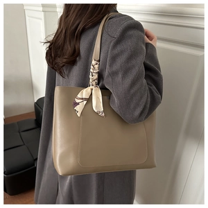 Detail of khaki tote bag featuring a textured PU leather finish and decorative silk scarf