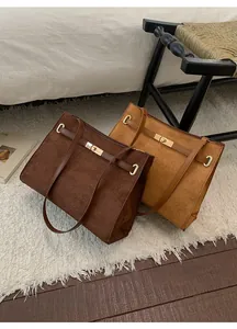 Détail de deux sacs cabas en daim marron foncé et kaki avec boucles dorées tournantes