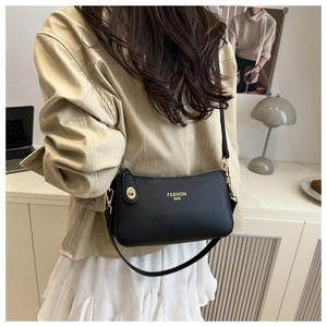 Detail of black pebbled leather crossbody bag with gold hardware and logo text