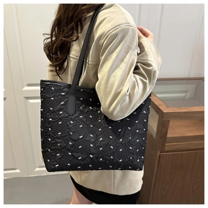 Détail du sac cabas noir à texture gaufrée orné de petits nœuds blancs décoratifs