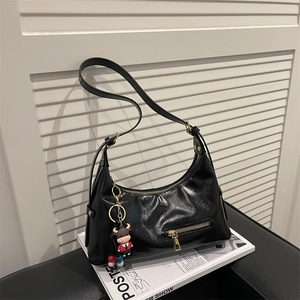 Minimalist black crescent leather tote bag with gold hardware and cartoon bull charm