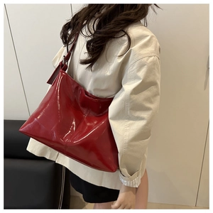 Dettaglio di una borsa tote in pelle verniciata rossa con finitura lucida e tracolla