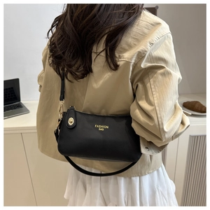 Detail of black pebbled leather crossbody bag with gold twist lock and metal logo