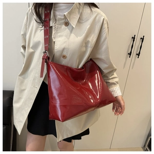 Dettaglio della grande borsa tote rossa lucida con tracolla regolabile e occhielli in metallo