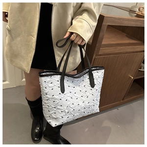Détail du sac cabas blanc avec motifs de nœuds noirs et texture en tissu plissé