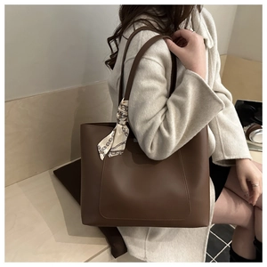 Detail of dark brown tote bag with decorative chain pattern silk scarf on the handle
