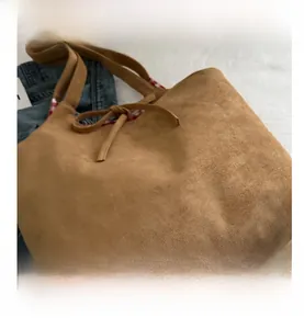 Detailed view of brown suede tote bag featuring contrast red and white checkered lining