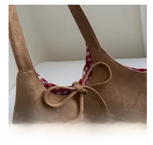 Detail of suede tote bag featuring brown finish with checkered lining and bow tie