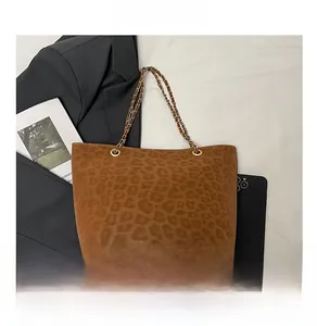 Détail du sac cabas léopard avec bandoulière en chaîne et œillets dorés sur blazer gris