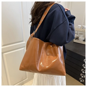 Dettaglio della borsa tote in pelle lucida caramello con tracolla larga e occhielli metallici