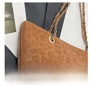 Détail de la texture léopard et de la bandoulière en chaîne dorée sur un sac cabas marron