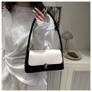 Détail d'un sac à bandoulière contrasté noir et blanc avec fermoir doré sur fond chaleureux