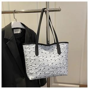 Détail du sac cabas blanc plissé à nœuds noirs suspendu sur un support d'exposition