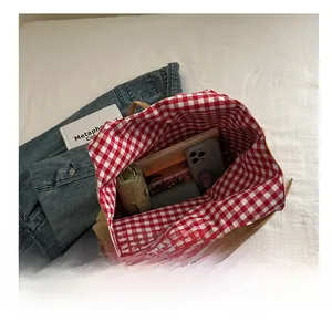 Macro view of high-capacity tote bag interior showing red-white plaid lining and storage