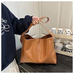 Dettaglio di una grande borsa tote marrone lucida che mostra la texture della pelle e la fibbia