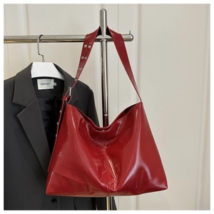 Dettaglio macro della borsa tote in vernice rossa con occhielli metallici sulla tracolla