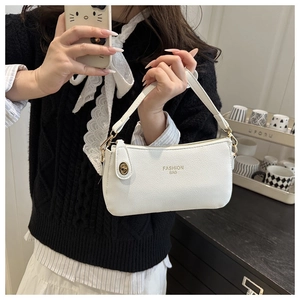 Detail of white lychee-textured small square bag with golden fashion branding and clasp