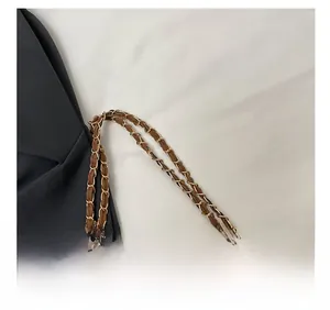 Détail d'une bandoulière en cuir marron avec une chaîne en métal doré pour sac à main