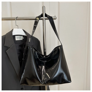 Dettaglio borsa hobo nera lucida appesa con tracolla regolabile con occhielli metallici