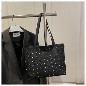 Détail du cabas noir matelassé avec motifs de nœuds blancs et tissu gaufré texturé