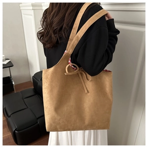 Detail of suede tote bag showing the ribbon bow closure and red checkered fabric lining