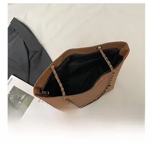 Détail d'un cabas marron avec chaîne dorée et fermeture éclair sur un blazer noir