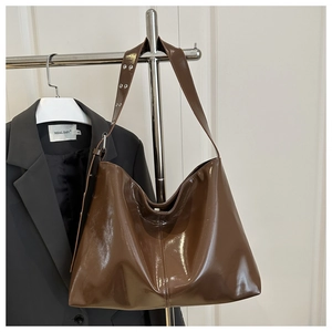Dettaglio della borsa hobo in vernice marrone lucida con tracolla larga e occhielli argento
