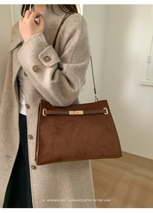Détail d'un cabas en daim avec fermoir doré et lanière en cuir sur un manteau
