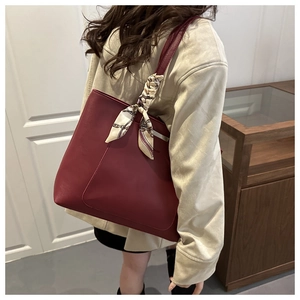 Detail of burgundy tote bag featuring a decorative silk scarf wrapped on the handle