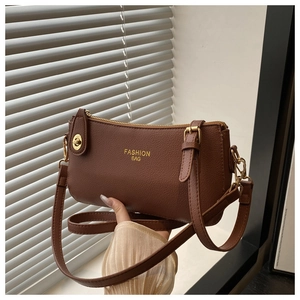 Detail of brown lychee grain leather crossbody bag with gold Fashion Bag lettering
