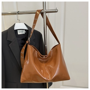 Dettaglio borsa hobo in pelle marrone lucida con tracolla e occhielli metallici