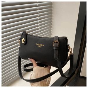 Close-up of black lychee-textured leather crossbody bag with golden hardware and fashion logo