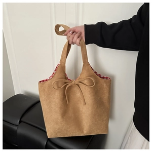 Detail of brown faux suede tote bag featuring a bow accent and red gingham lining
