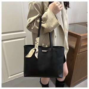 Detail of black tote bag with silver bar, printed scarf on handle and fashion engraving