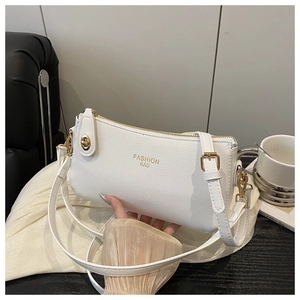 Detail of white cross-body bag with pebble grain leather and gold Fashion Bag logo
