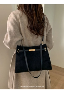 Détail du fermoir en métal doré et texture en daim sur un sac cabas noir rétro