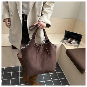 Close-up of brown suede tote bag with drawstring bow detail and checkered lining