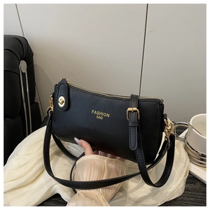 Detail of black pebbled leather handbag with gold Fashion Bag text and zip hardware