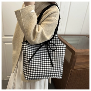 Detail of checkered tote bag with black bow tie, soft canvas texture and large capacity