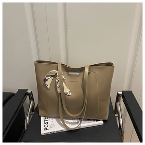Detail of khaki large tote bag with metallic buckle and decorative silk scarf handle