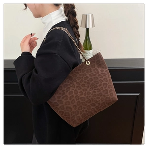 Détail du sac cabas léopard avec bandoulière en chaîne dorée sur l'épaule du mannequin