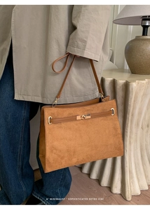 Détail du sac cabas en daim marron avec fermoir tournant en métal doré et boucle d'anse