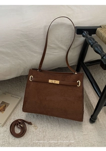 Gros plan d'un sac cabas en daim marron avec fermoir pivotant en métal et sangle en cuir