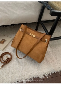 Détail du sac cabas en daim marron avec fermoir rotatif doré et fine bandoulière chic