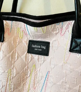 Detail of pink jacquard tote bag featuring wave stitching and black leather logo patch